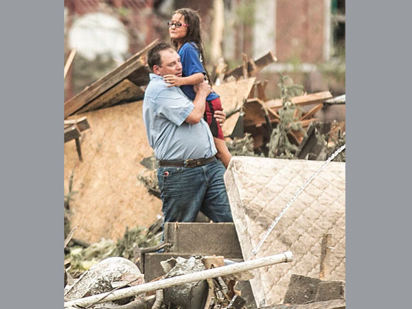 A man holds a girl after she was pulled from the basement 