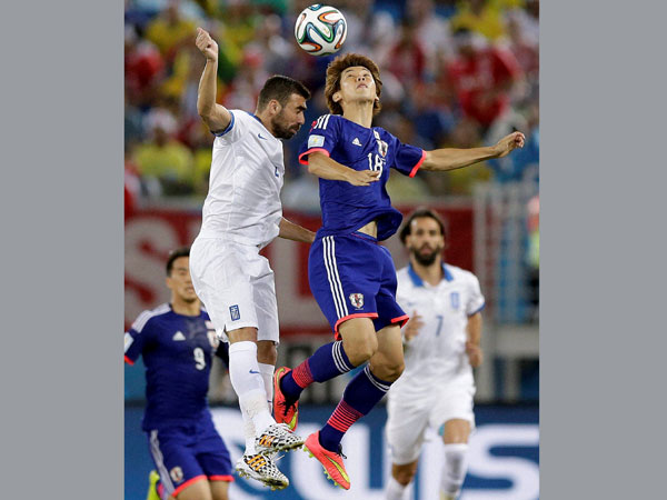 Japan's Yuya Osako, right, is challenged for a high ball