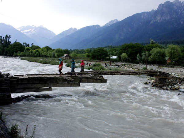 People cross an old wooden bridge built over Sindh river 