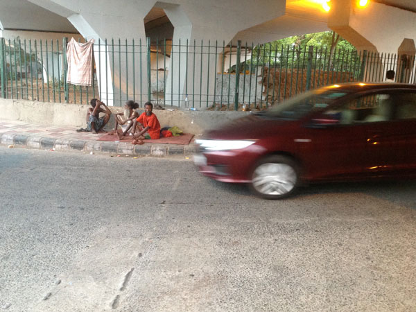 Three old persons sitting under a flyover 