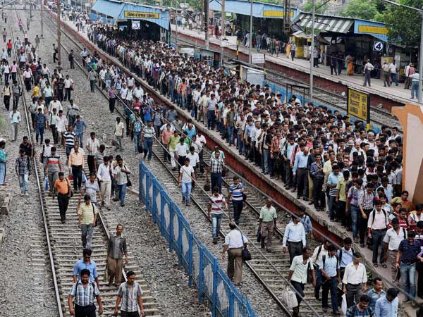 Commuters walk at platform and tracks at a railway station