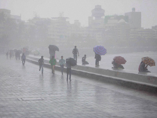 People walk in heavy rains at Marine Drive in Mumbai