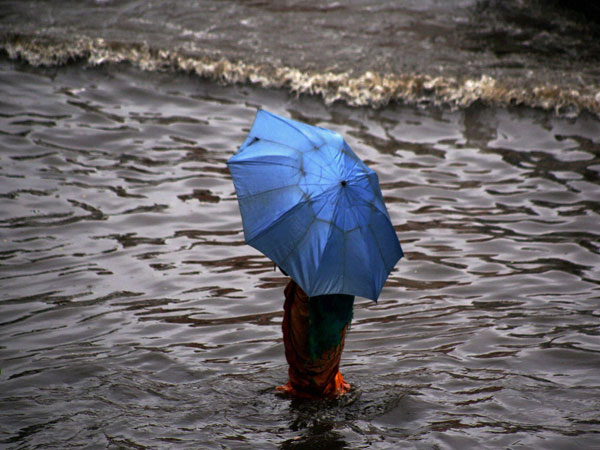 A woman walks with an umbrella at waterlogged street