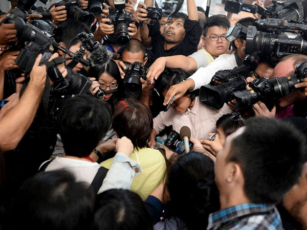 Members of the media surround a relative of a passenger on board 