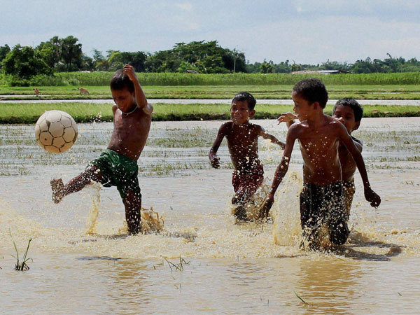 Children playing football in a waterlogged field