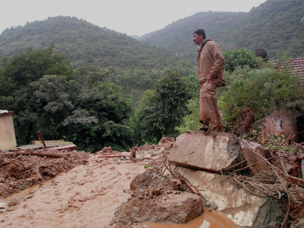 A rescuer looks at the debris at the site of a landslide
