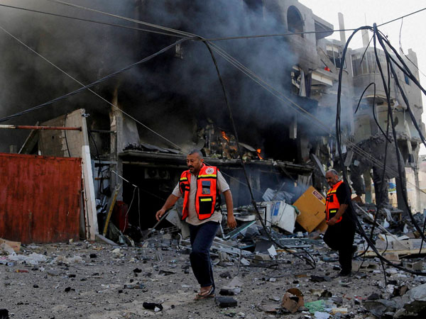 Palestinian firefighters inspects the damage of a destroyed milk factory