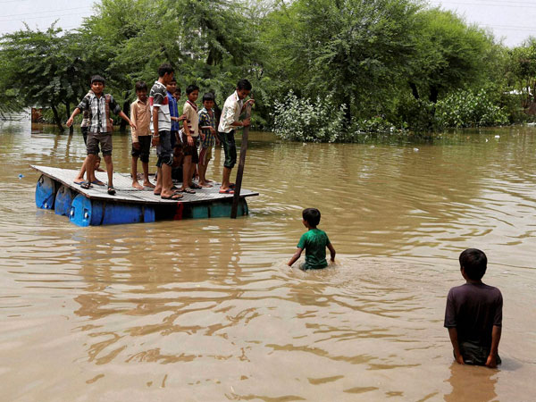 Children use a temporary raft to shift in a flooded village