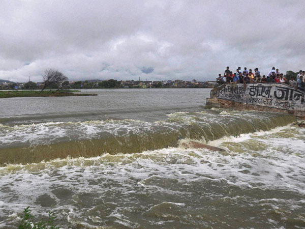 People looking at rushing water after heavy rainfall People looking at rushing water after heavy rainfall