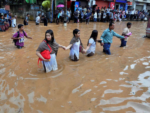 People holding each others hands to move across a waterlogged road