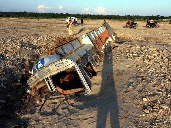 People watch a truck that was covered by a landslide