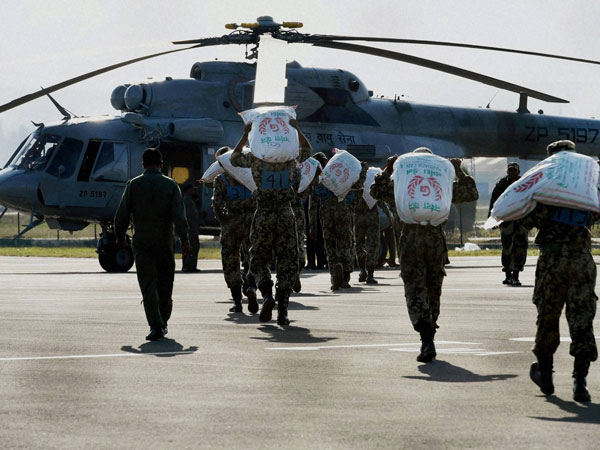 Army personnel load relief materials in a chopper