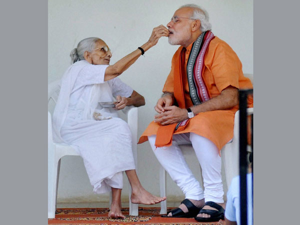 Prime Minister Narendra Modi is offered sweets by his mother