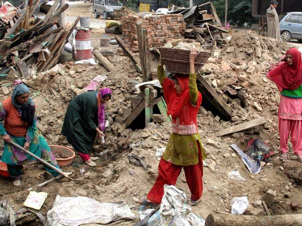 Women clearing the debris of a collapsed house