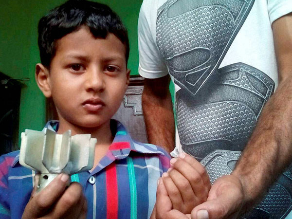 A boy shows a mortar shell following firing at village