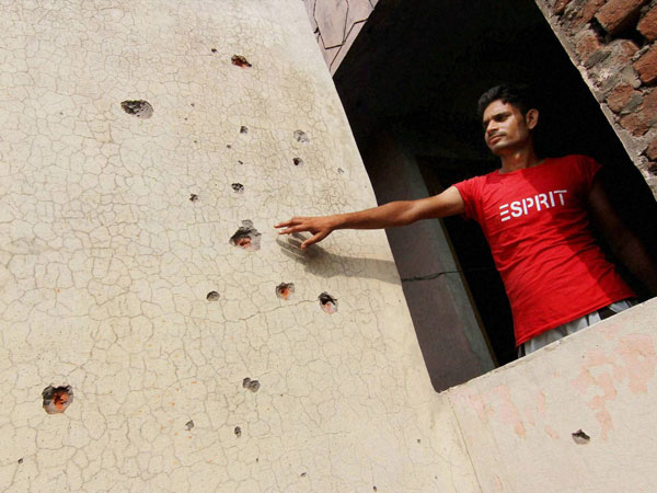 A man shows the bullet marks on a wall 
