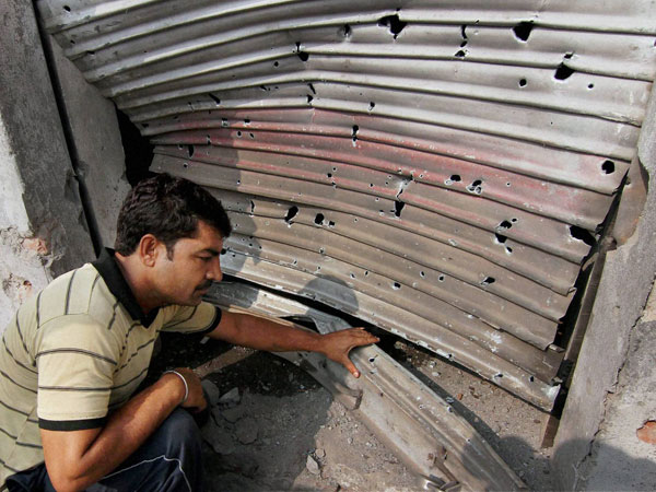 A villager shows the bullet marks on a shutter of a shop 