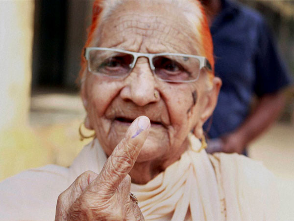 An elderly woman shows her ink-marked finger