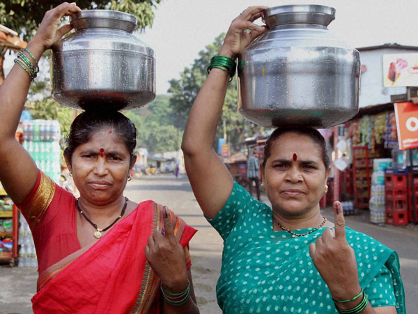 Women display their inked fingers as they carry water