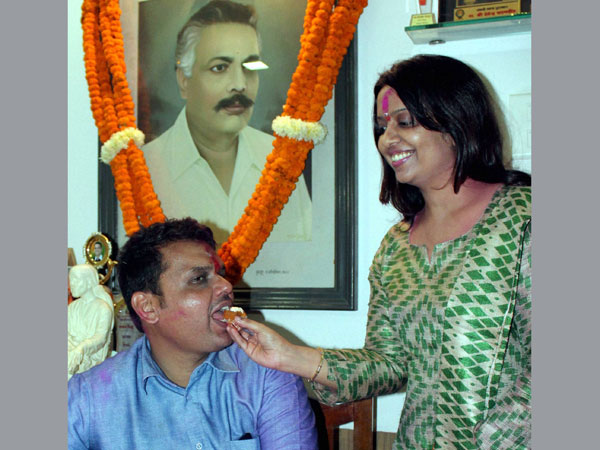 Devendra Fadnavis being offered sweets by his wife Amruta