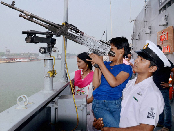 A naval officer helps a school girl to have a look 