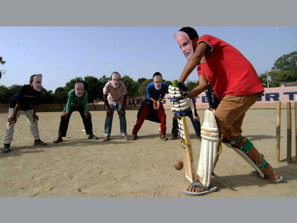 Boys wearing mask of Narendra Modi playing cricket