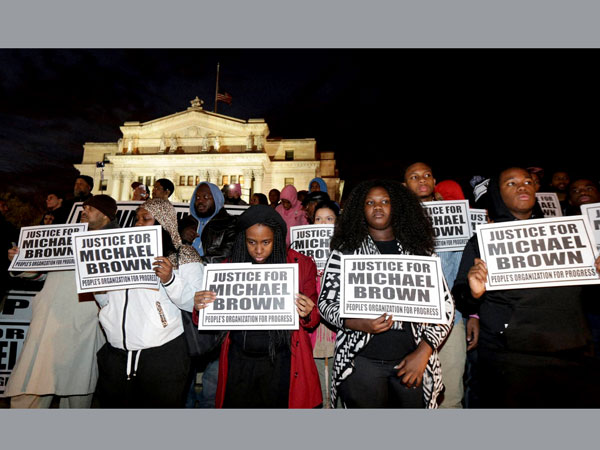 People hold signs during a rally in response to news of a grand jury