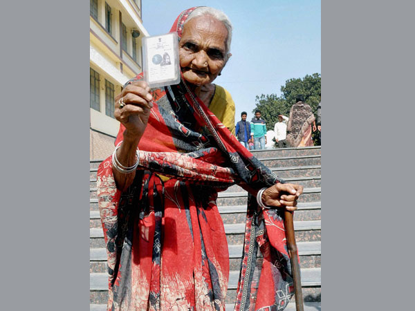 An elderly woman shows her voter card