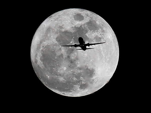 A commercial airliner crosses the first full Moon of the year