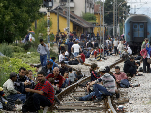 Migrants sit on the tracks at the railway station