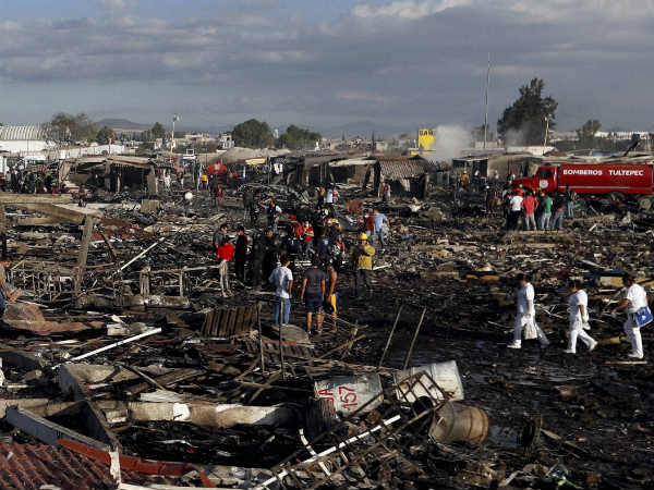 Firefighters, rescue workers walk along the charred remains of the market