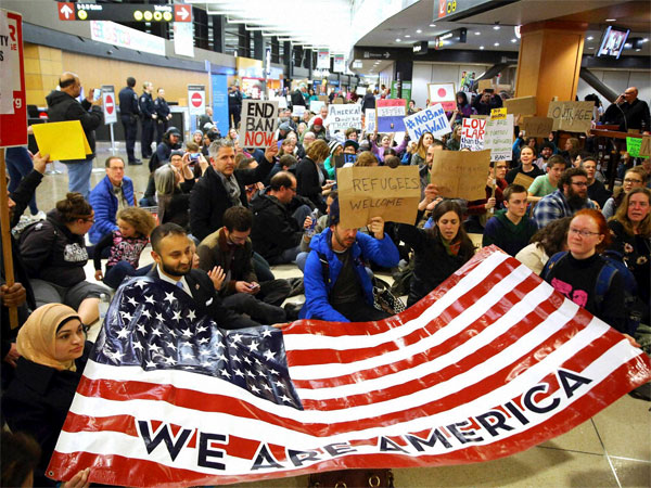 Demonstrators sit down in the concourse and hold a sign that reads Demonstrators sit down in the concourse and hold a sign that reads