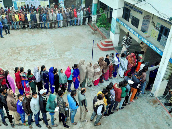 A security person stands guard as voters stand in queues A security person stands guard as voters stand in queues