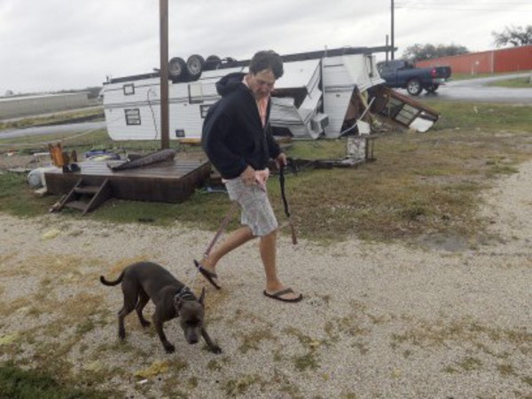 A man walks past an trailer overturned by the winds