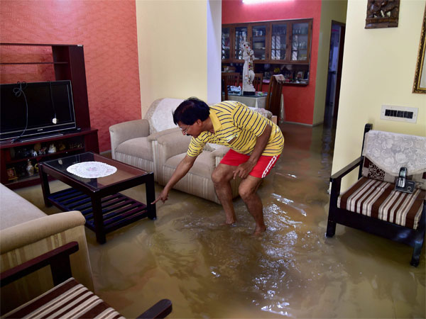 A resident wades through the clogged rain water at his house in low-lying locality in Bengaluru