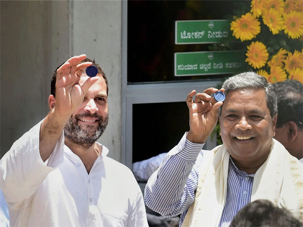 Congress Vice President Rahul Gandhi and Karnataka Chief Minister Siddaramaiah show a token during the inauguration of 'Indira Canteen' in Bengaluru