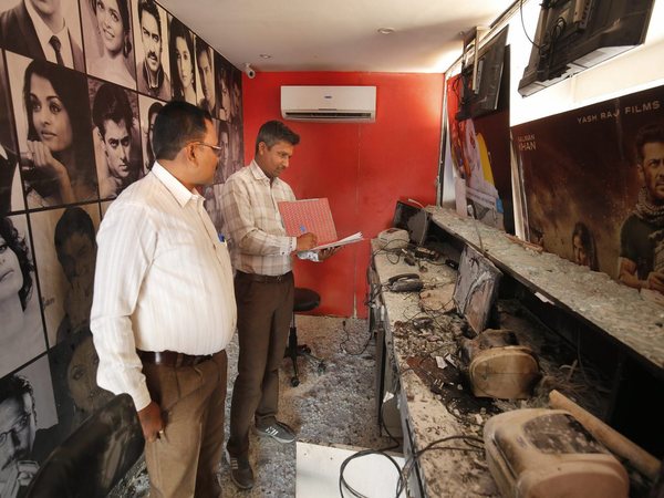Forensic experts examine the ticket counter of a cinema hall after it was vandalised in Ahmedabad
