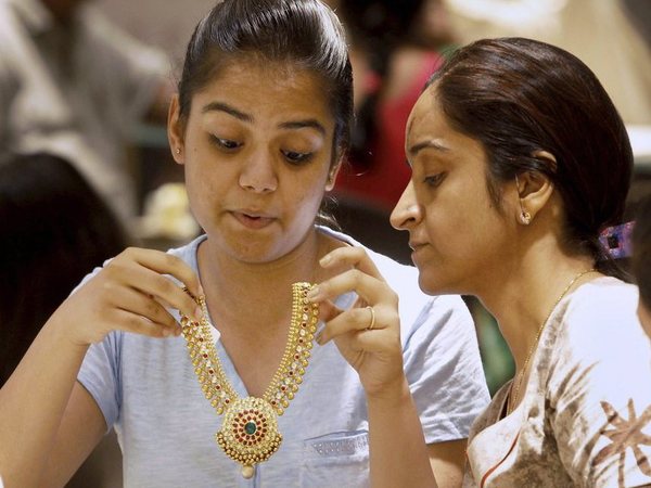 A girl tries a gold necklace inside a jewellery showroom