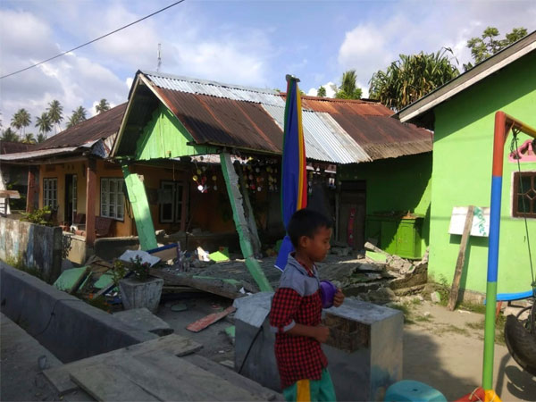 People walk past the damaged buildings