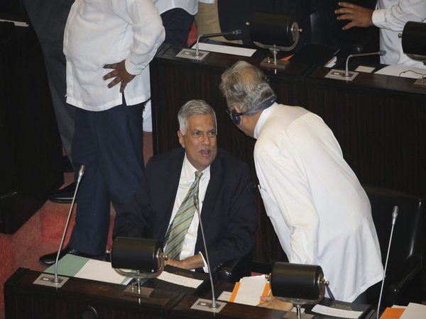 Ranil Wickremesinghe speaking with a lawmaker inside Parliament in Colombo