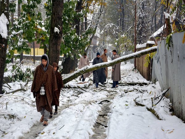 People walk on a snow covered road after heavy snowfall in Anantnag