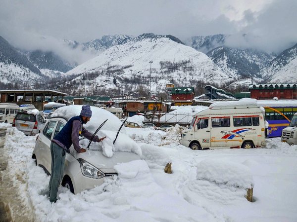 Man clearing snow off a car near Banihal railway station