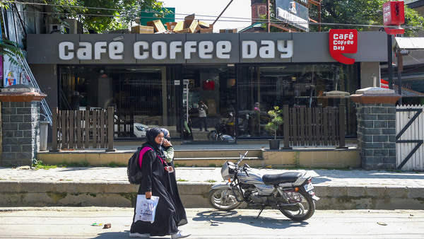 Women walk past a closed Cafe Coffee Day shop in Srinagar, Wednesday, July 31, 2019.