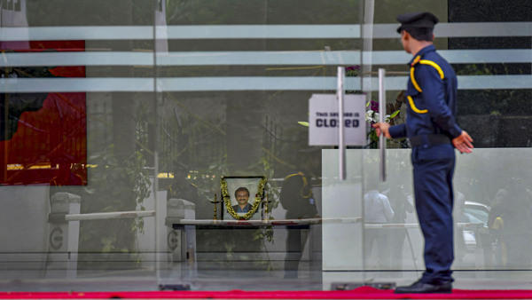 A security person guards at a Cafe Coffee Day outlet as a poster of its founder V.G. Siddhartha is placed for paying tribute to him, in Bengaluru, Wednesday, July 31, 2019. 