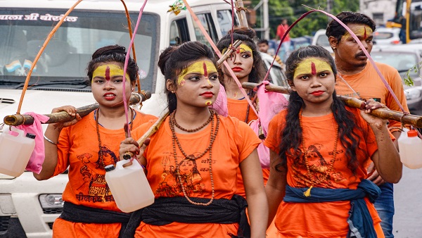 Women Kanwariyas carrying 'Kanwad' pass through a street