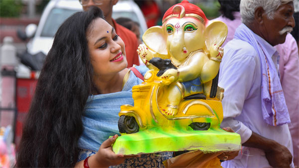 A devotee carries a Ganesh idol on the eve of the Ganesh festival A devotee carries a Ganesh idol on the eve of the Ganesh festival