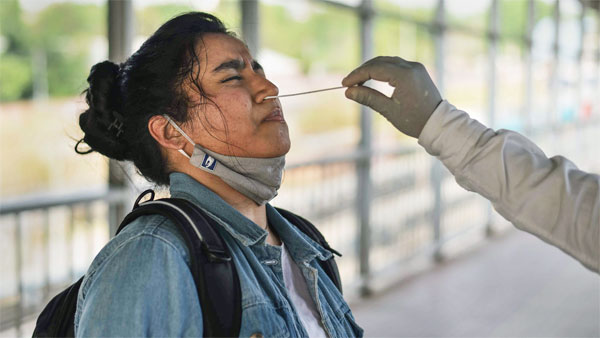 A healthcare worker collects a swab sample of a passenger for Covid-19 testing A healthcare worker collects a swab sample of a passenger for Covid-19 testing