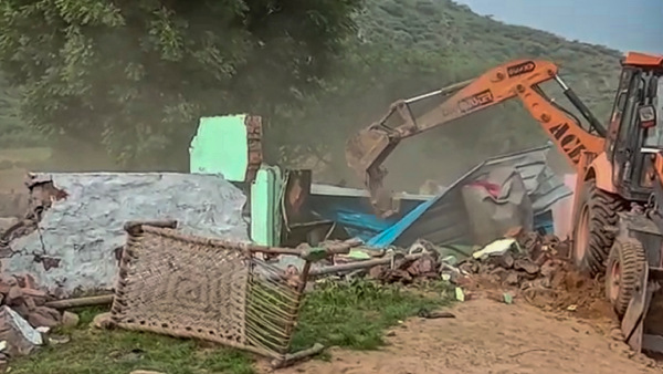 A bulldozer demolishes alleged illegal constructions after orders from the district administration, in Nuh district