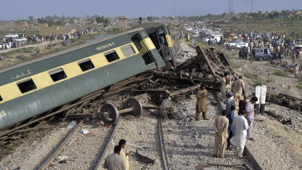 Local residents examine damaged cars of a passenger train which was derailed near Nawabshah, Pakistan