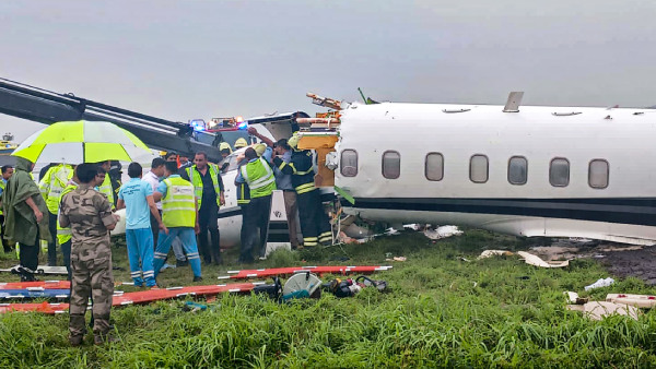 Officials gather around a damaged aircraft after it veered off the runway with six passengers and two crew members on board at the Mumbai airport amid heavy rains, in Mumbai